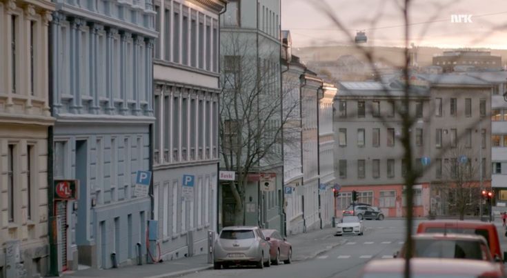 cars are parked on the side of an empty street in front of tall buildings at sunset