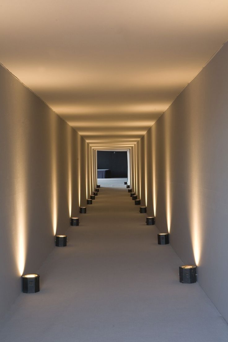 an empty hallway with several lights on either side and one light at the end that is lit up