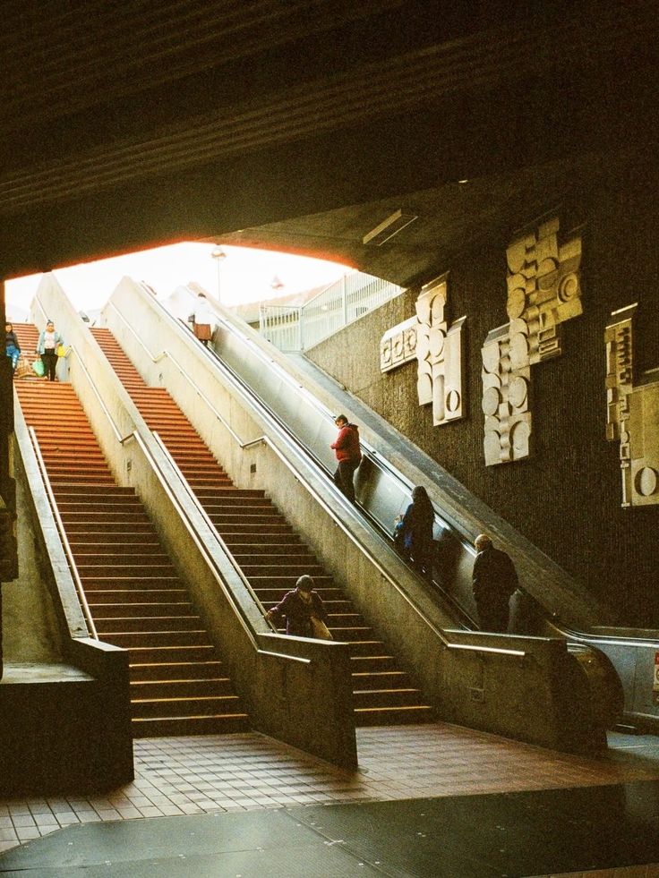 people are riding down an escalator with their luggage on the ground below them