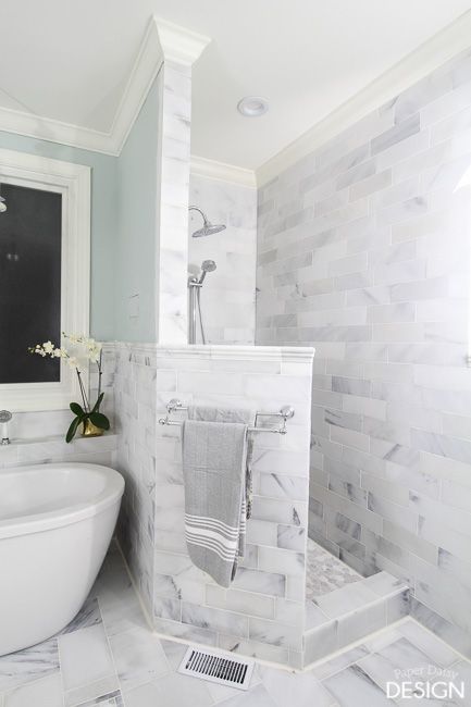 a white bathtub sitting next to a sink in a bathroom under a mirror on the wall