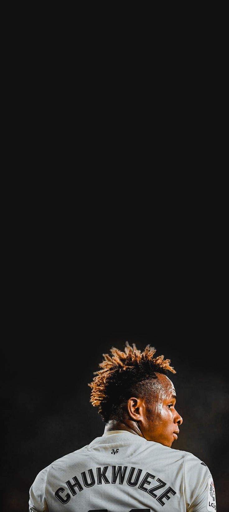 a man with dreadlocks standing in front of a soccer ball