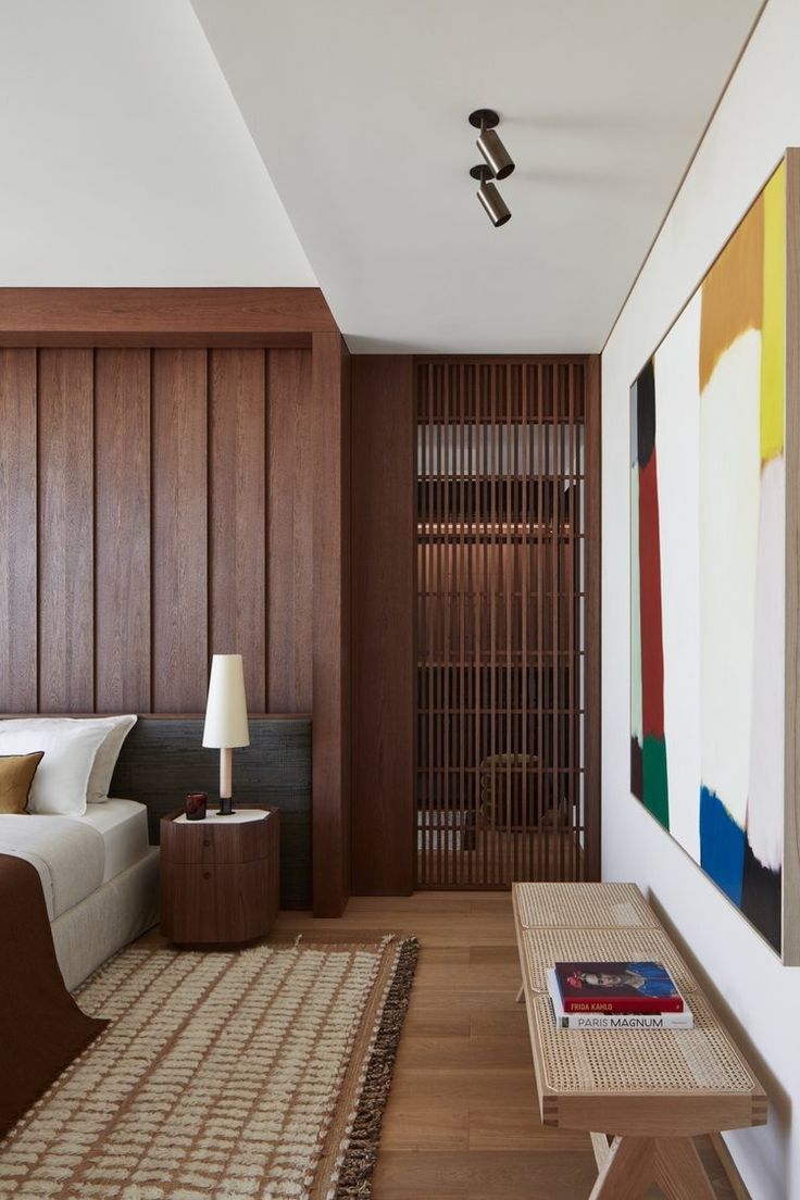 a room with wood paneling and a painting on the wall next to a bed