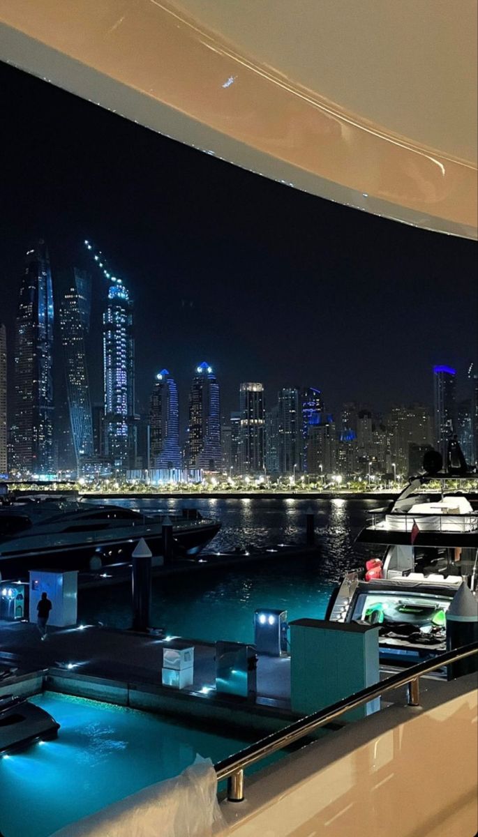 a boat is docked in the water near some buildings and boats at night with city lights