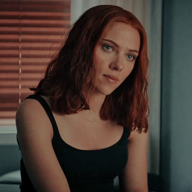 a woman with red hair sitting in front of a window