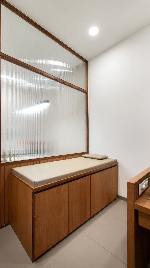 an empty room with a wooden bench and glass window on the wall, in front of a white tiled floor