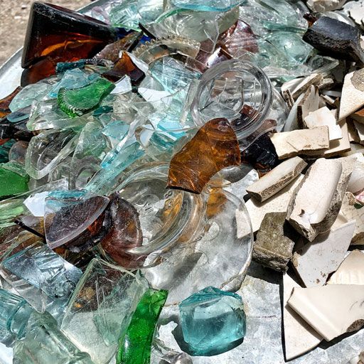 many different colored glass pieces on top of each other and one green bottle in the middle