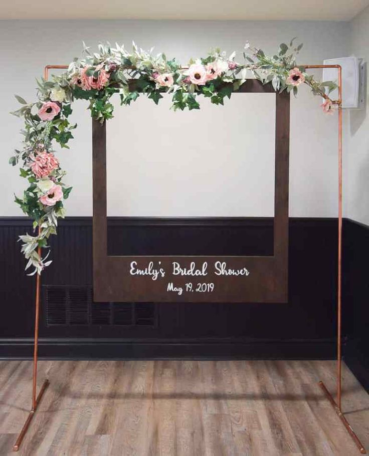 a wedding arch decorated with pink flowers and greenery for the bride's bridal shower