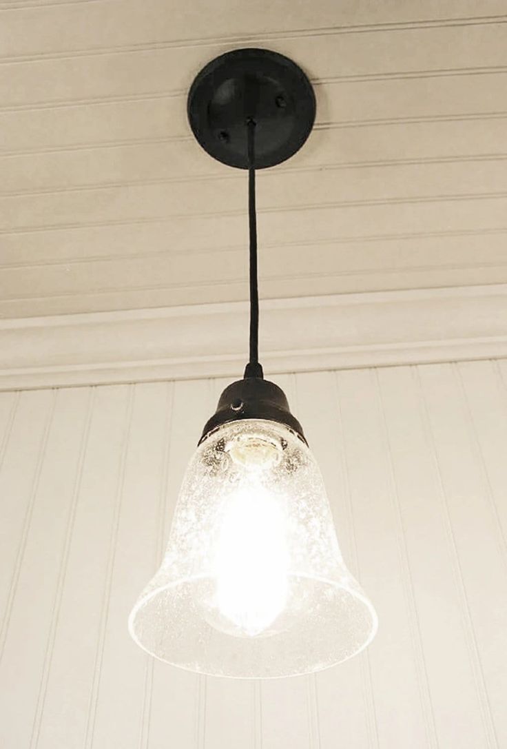 a light fixture hanging from the ceiling in a room with white walls and wood paneling