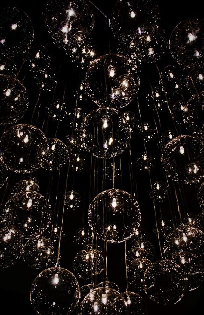 a chandelier made out of glass balls hanging from it's ceiling in the dark