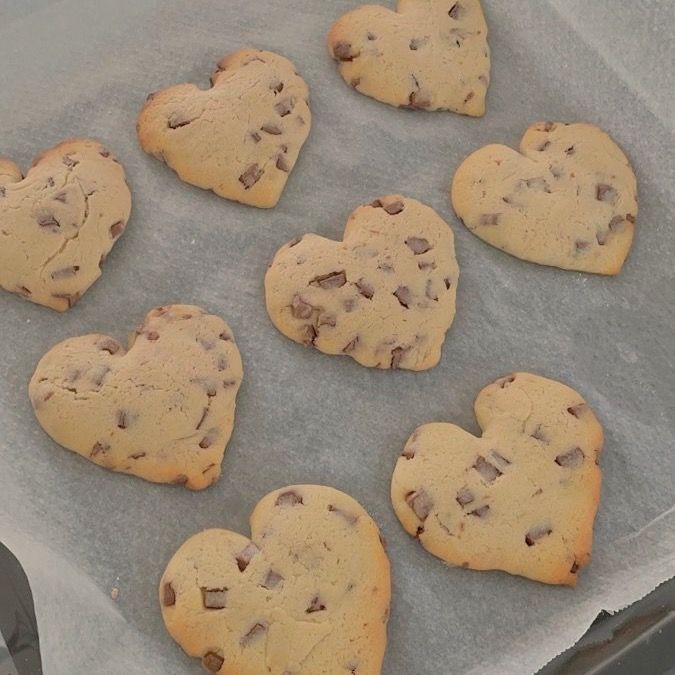 chocolate chip cookies in the shape of hearts on a baking sheet