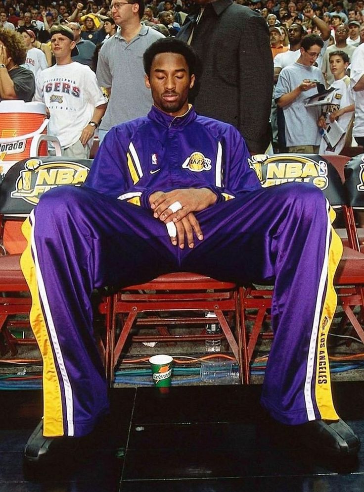 a man sitting on top of a bench in front of a crowd at a basketball game