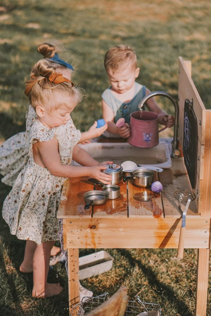 "Get ready for some messy and imaginative playtime with this wooden Mud Kitchen from GCR Wooden Creations! Crafted with care, this toy is perfect for children who love to pretend and create their own little adventures. The inclusion of a fully functional faucet enhances the play experience, allowing your little ones to engage in water activities as they concoct mud masterpieces.   Made with cedar wood and built to withstand outdoor play, this mud kitchen will provide endless hours of entertainment for your little one.  Encourage imaginative play, sensory exploration, and a love for the outdoors with our Mud Kitchen - where the joy of nature meets the creativity of childhood.   The mud kitchen is 35\" long x 35\" high x 20\" deep.  The playing surface is 20.5\" tall.  All appearance boards Outdoor Mud Kitchens For Kids, Montessori Outdoor Play, Mud Kitchen For Kids, Indoor Playground Design, Action Board, Wooden Creations, Kitchen Water, Sensory Exploration, Outdoor Play Areas