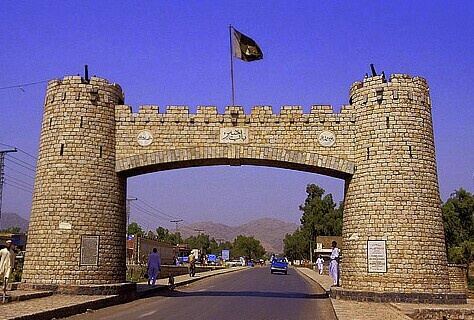 an old stone gate with two flags on top