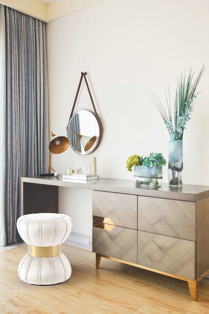 a white and gold dresser in a room with a mirror on the wall next to it