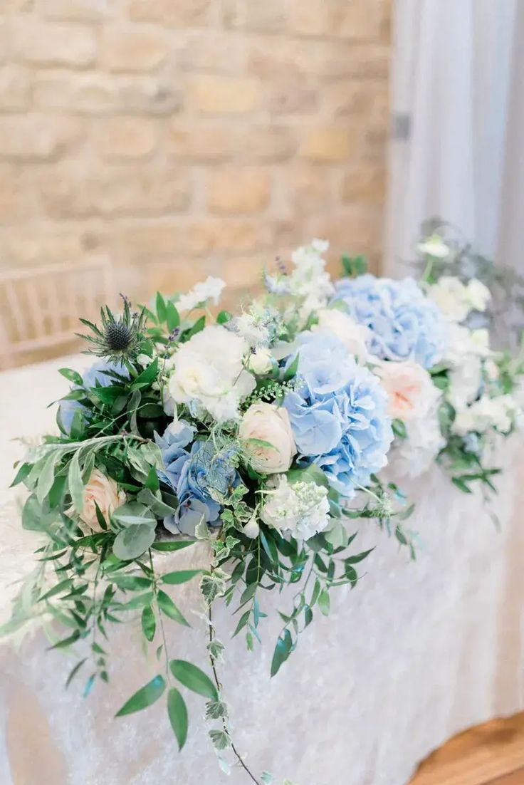 blue and white flowers are arranged on the table for an elegant centerpiece at this wedding reception