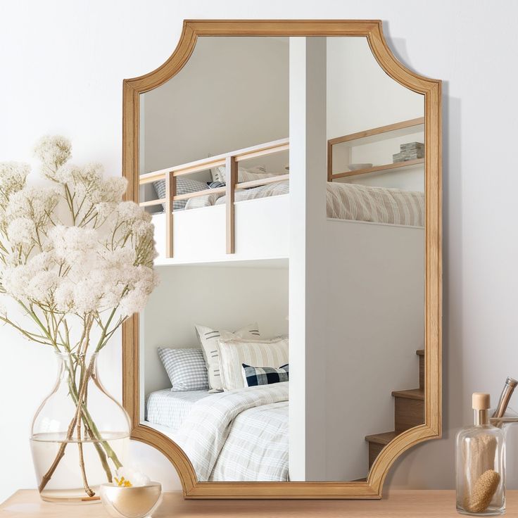 a mirror sitting on top of a table next to a vase with flowers in it