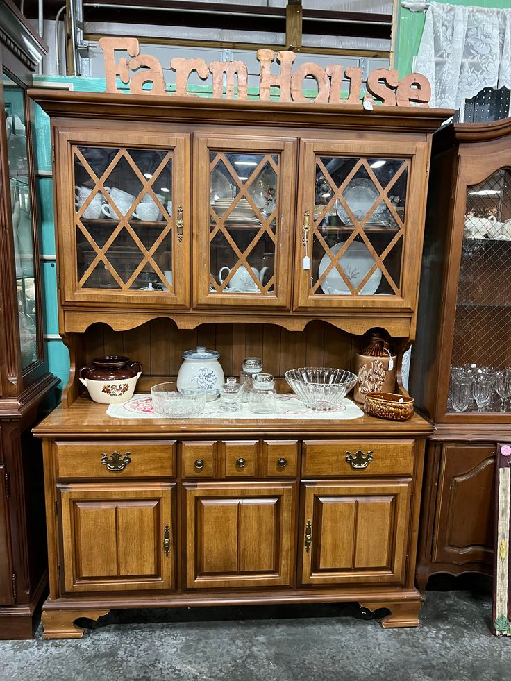 a wooden china cabinet with glass doors and drawers on display in a store or showroom