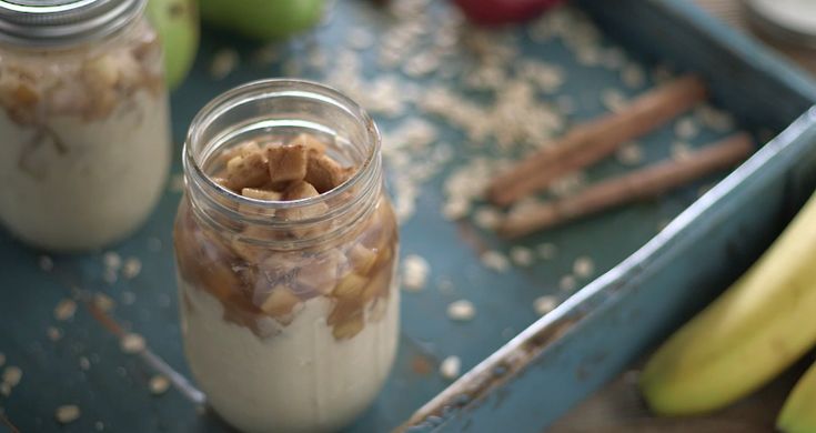 two jars filled with oatmeal sitting on top of a table next to bananas