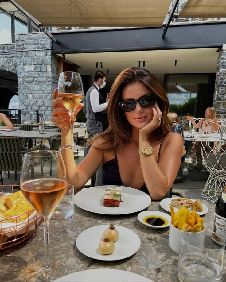 a woman sitting at a table with food and drinks