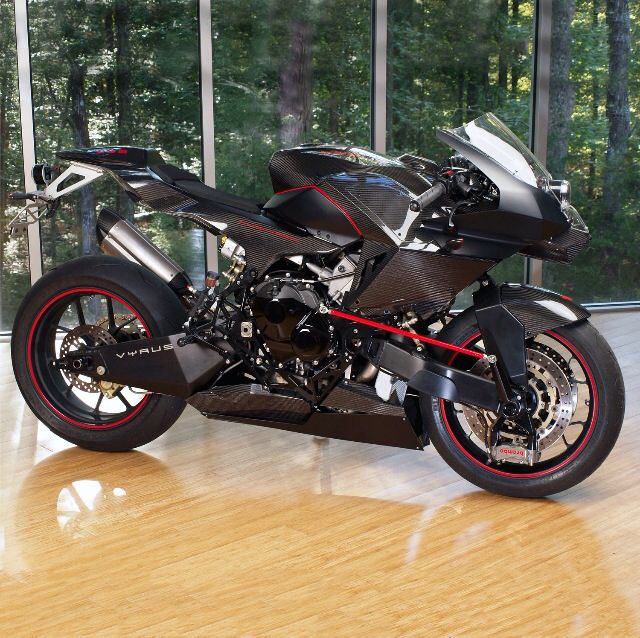 a black motorcycle parked in front of a window on top of a hard wood floor