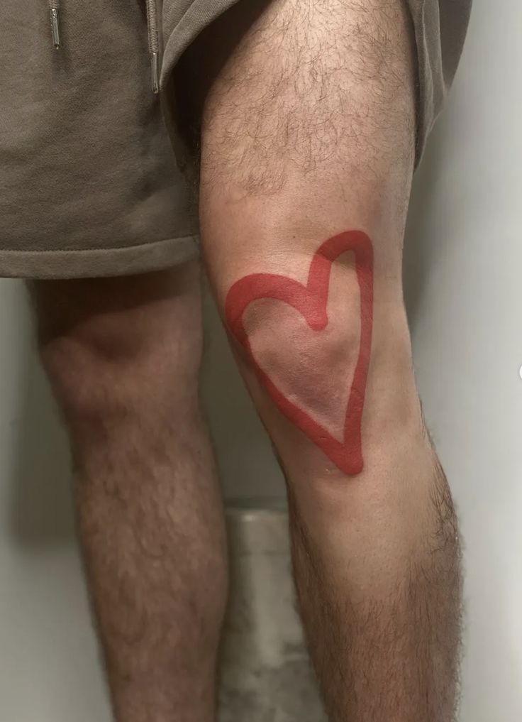 a man with a red heart tattoo on his leg