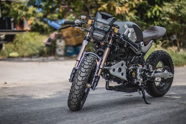 a black motorcycle parked on the side of a road next to some bushes and trees