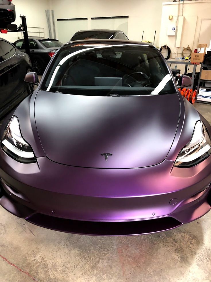 a purple car parked in a garage next to other cars