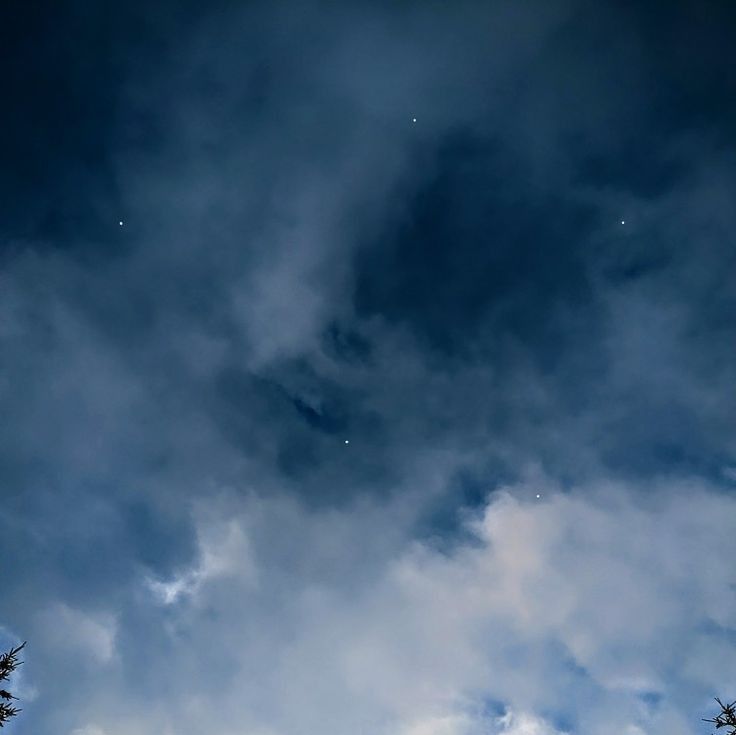 the sky is filled with clouds and stars as well as some trees in the foreground