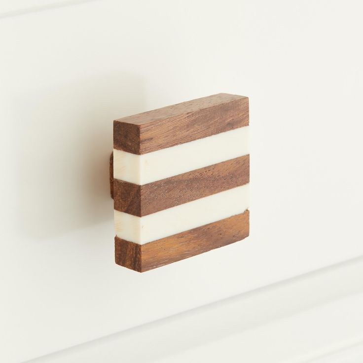 a wooden block mounted to the side of a white wall next to a brown and white object