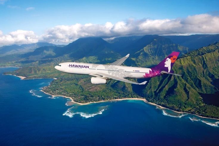 an airplane is flying over the ocean and mountains in this aerial photo, with its landing gear down