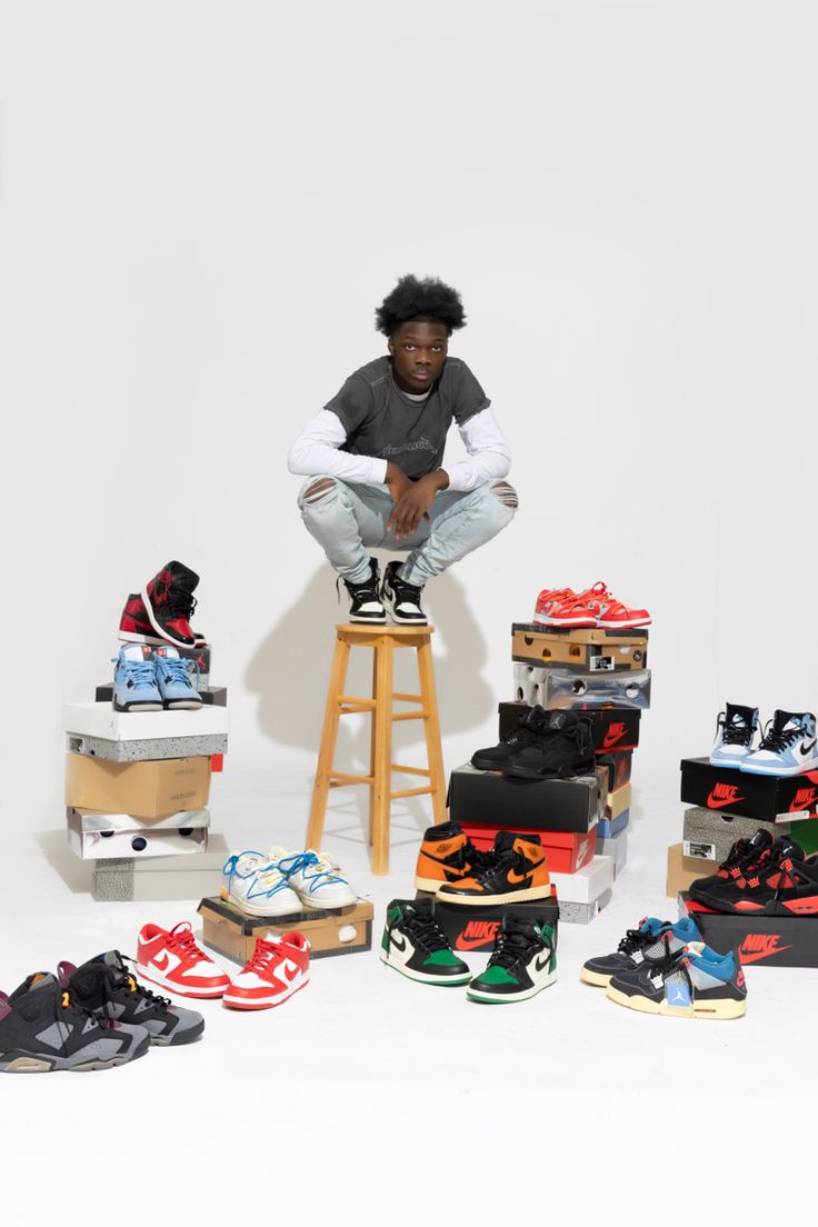 a man sitting on top of a stool surrounded by shoes