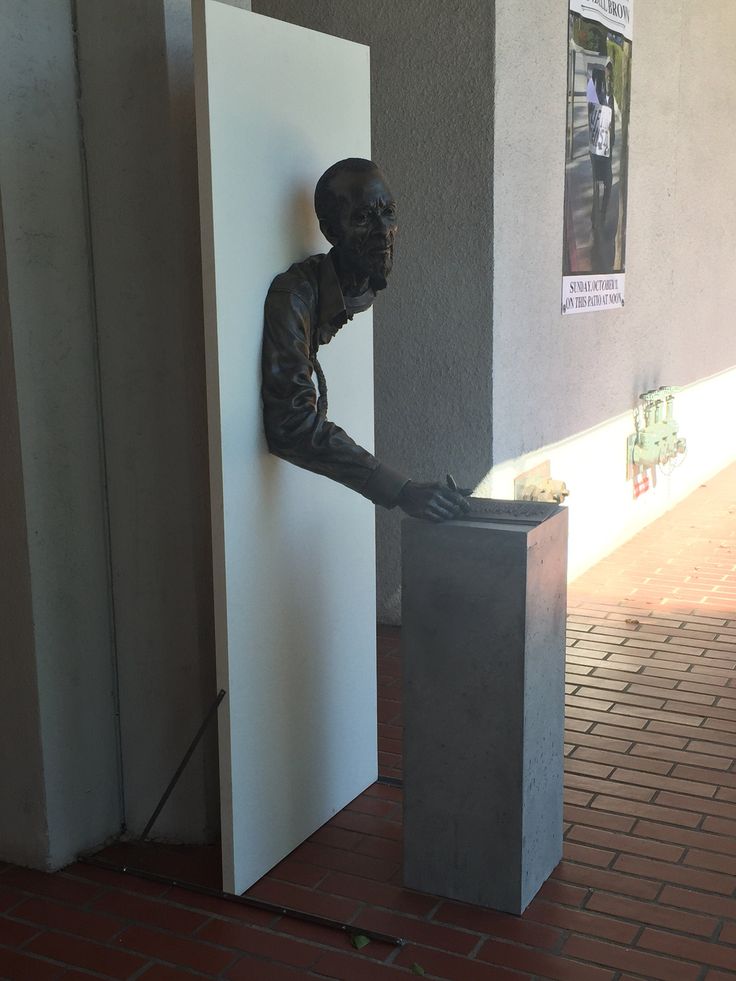 a statue of a man is next to a white box on the side of a building