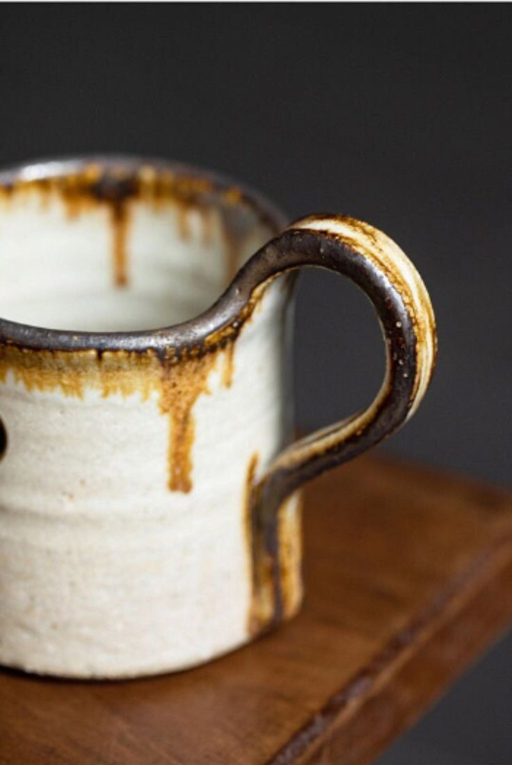 a brown and white cup sitting on top of a wooden table