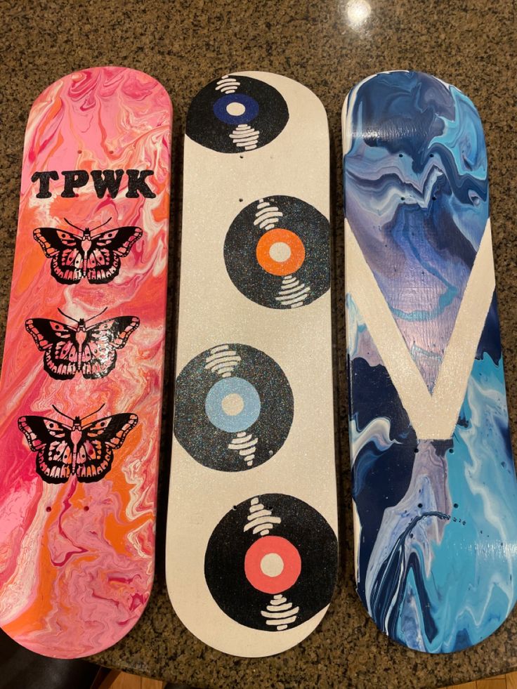 three skateboards with different designs on them sitting next to each other in a row