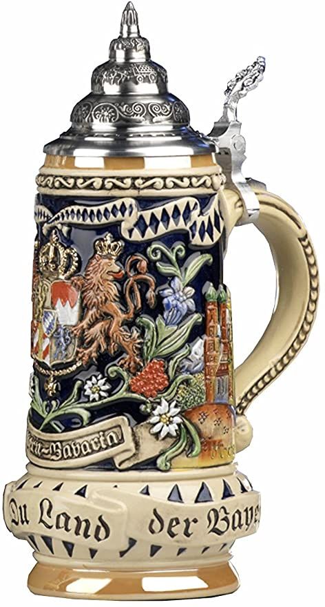 a beer mug with an ornate design on the front and sides, sitting next to a black box