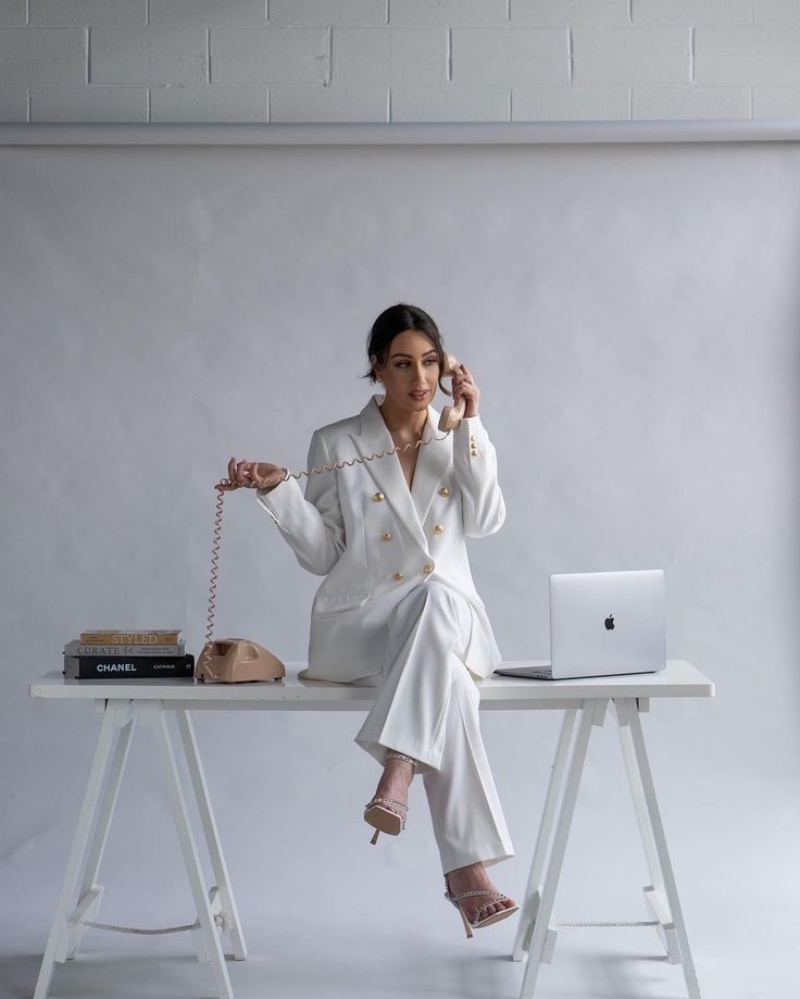 a woman sitting at a desk with a laptop and phone in her hand, holding a string