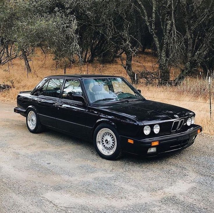 a black bmw is parked in front of some trees