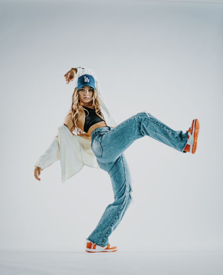 a woman in jeans and a baseball cap is doing a trick