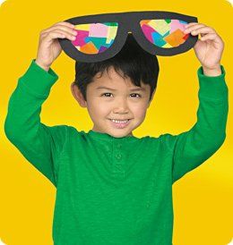 a young boy is holding up sunglasses to his face