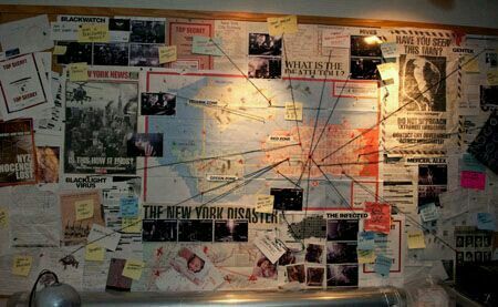 a wall covered in papers and pictures with lights on it's sides is shown