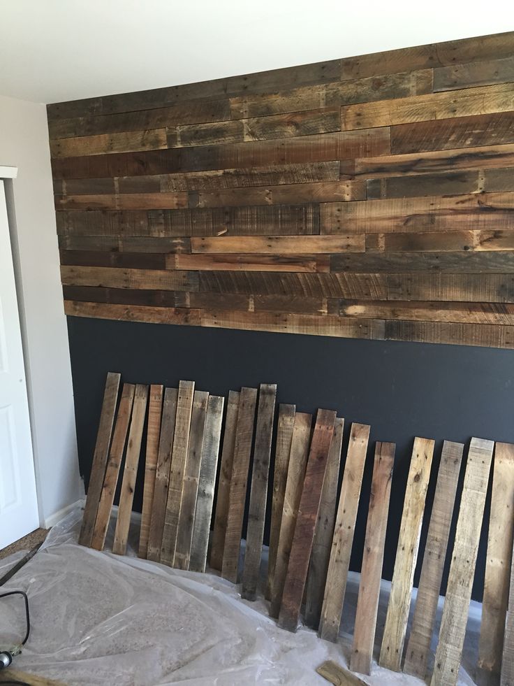 some wood pallets are laying on the ground in front of a wall with a wooden plank