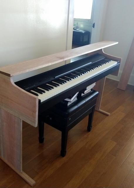 a piano sitting on top of a hard wood floor next to a wall with a window