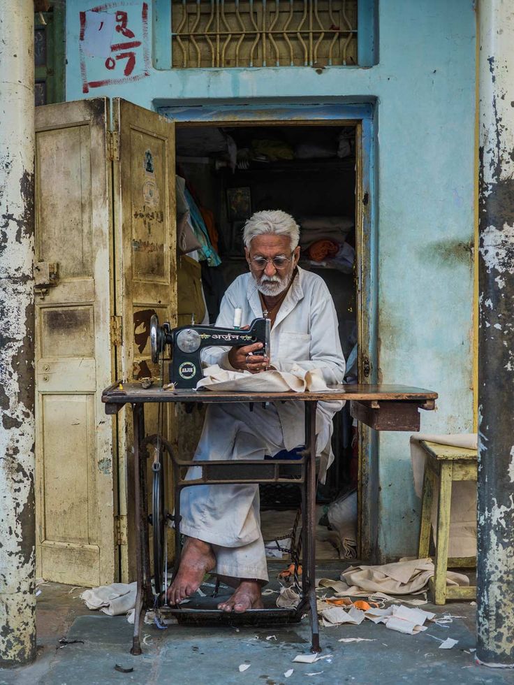 an old man sitting at a sewing machine