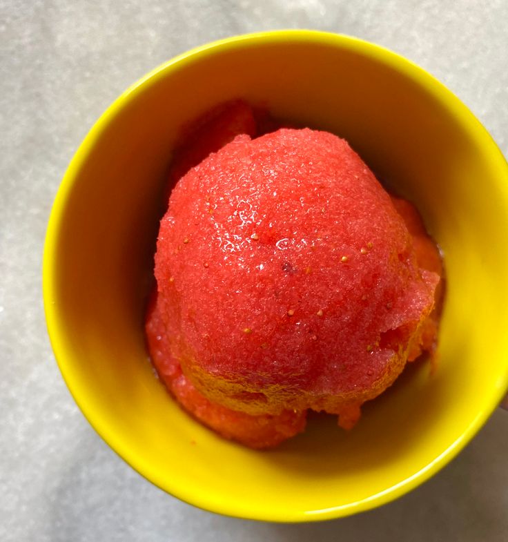 a yellow bowl filled with watermelon on top of a table