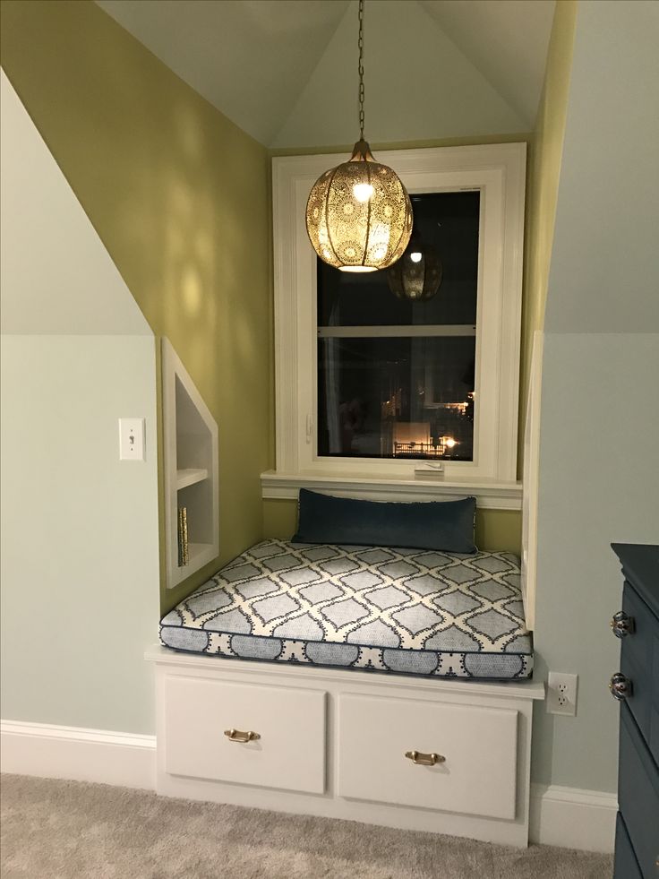 a small bed with drawers underneath a window