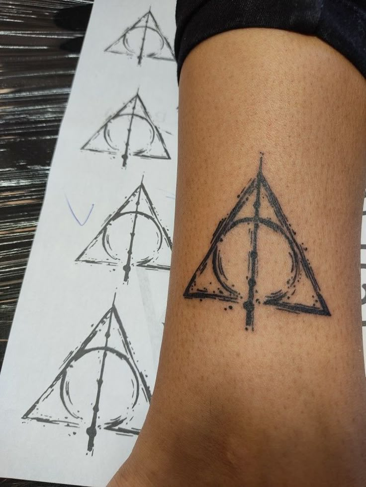 a harry potter symbol tattoo on the right side of the leg, with other symbols behind it