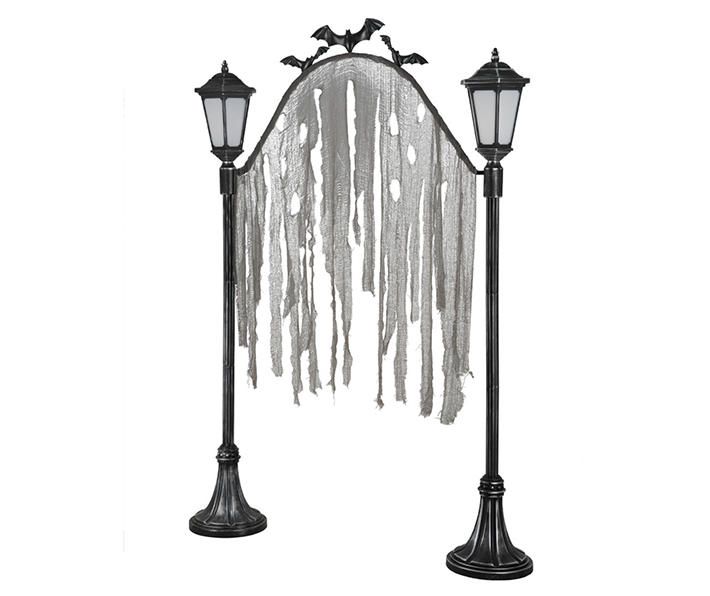 two black street lamps with white drapes hanging from it's sides and birds perched on them