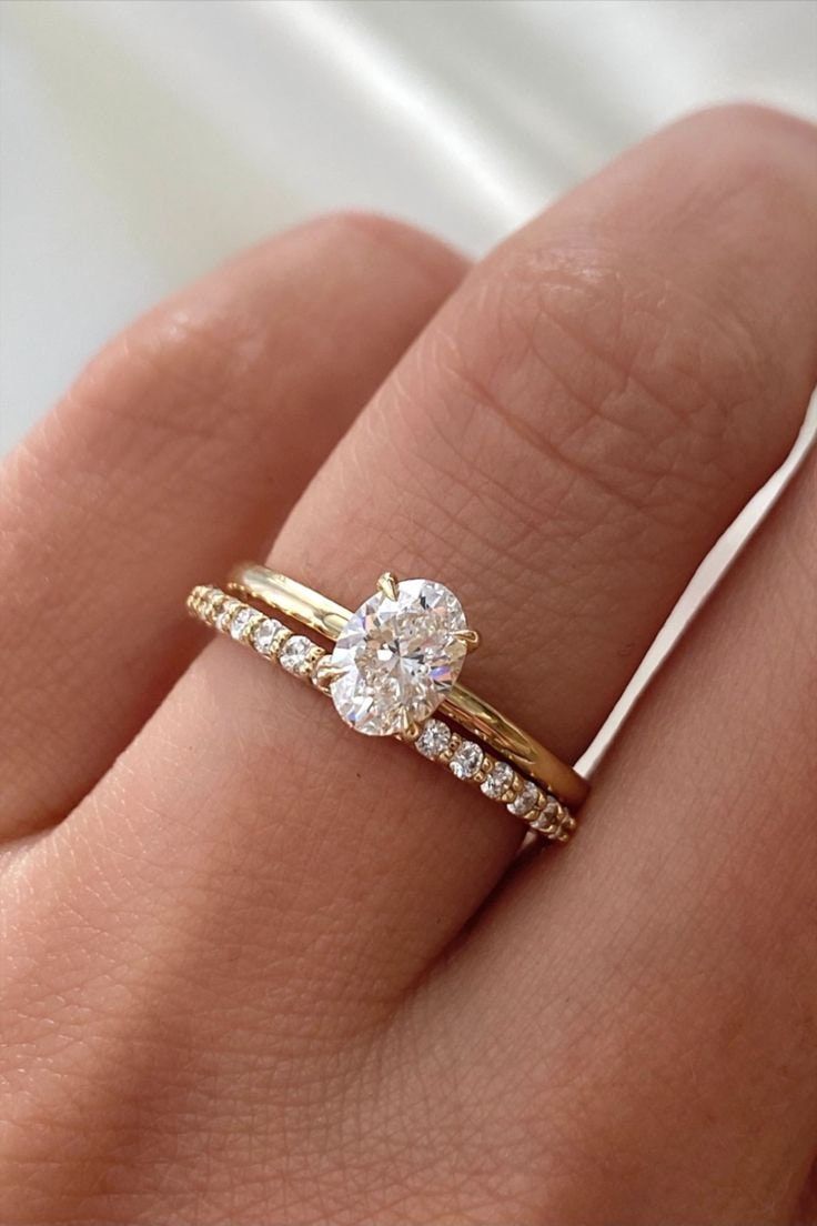 a woman's hand with two gold rings and a diamond ring on top of her finger