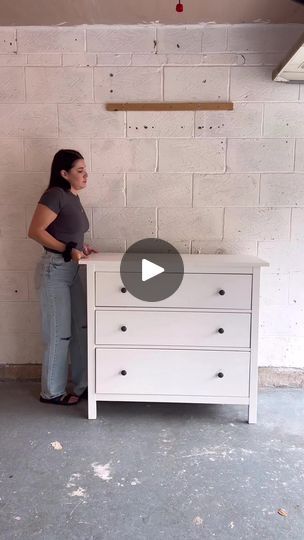 a woman standing next to a white dresser