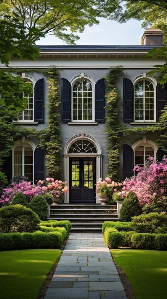 a large house with lots of windows and plants on the front door, along with steps leading up to it